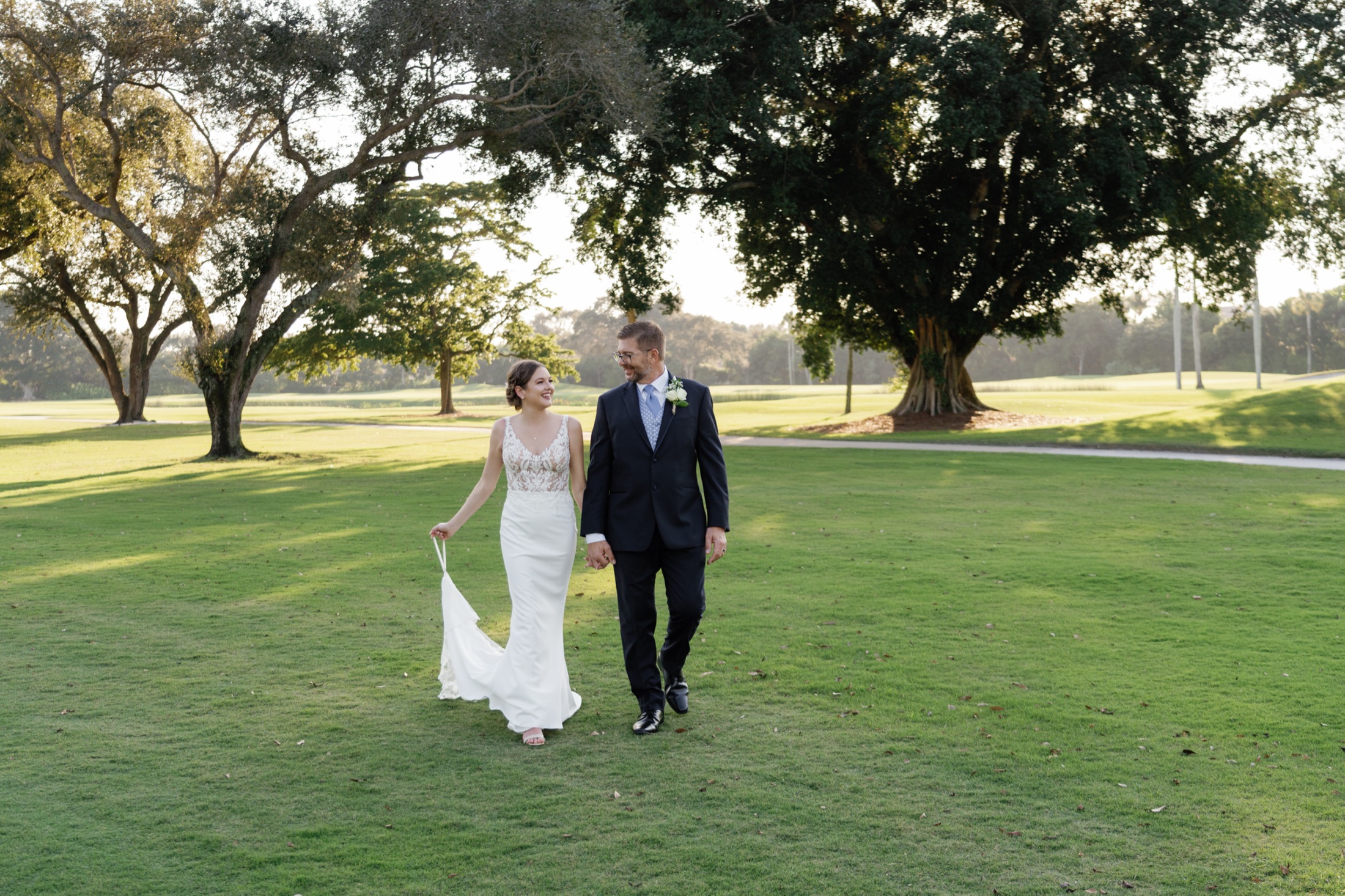 A couple walks through golden Florida light on their wedding day